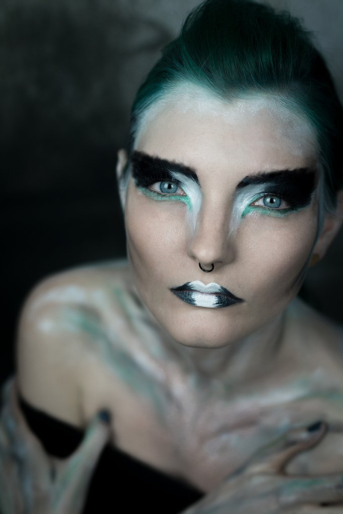 Portrait of model Lexa Throk showcasing experimental turquoise green and white makeup, evoking the spirit of an abstract falcon lady.