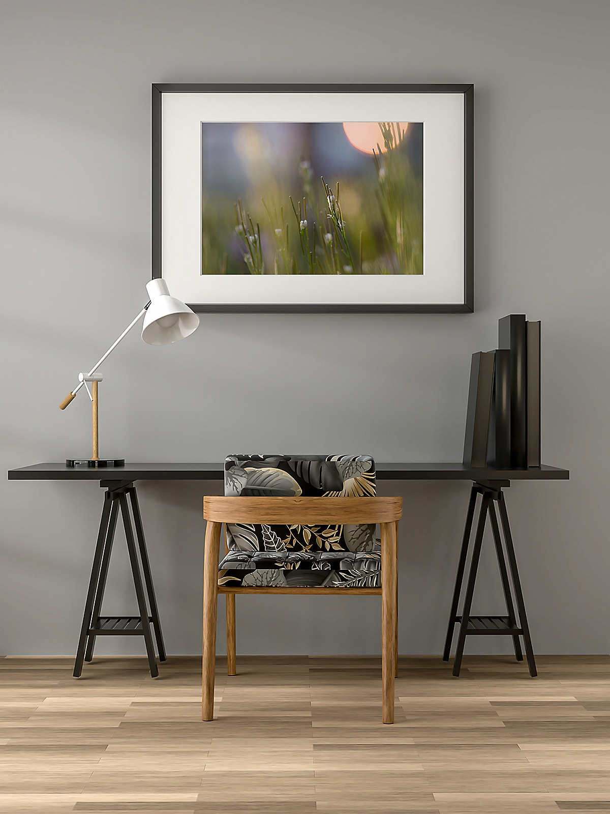 Multiple Cardamine pratensis flowers in a grassy field under a setting sun in the right corner, with purple hues in the sky, framed in a black frame with white mount, hanging on a grey colored wall, with a black office table underneath and a luxurious patterned chair.