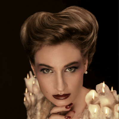 With model Anna Povarova, experience the fusion of past elegance and modern artistry. Hairstyling, make-up and props by Anett Alexandra Bulano. 🕯️✨ #GibsonGirl #ModernElegance #ArtisticVision A modern reinterpretation of the Gibson Girl hairstyle, featuring the model Anna Povarova with burning wax candles arranged as shoulder pads.