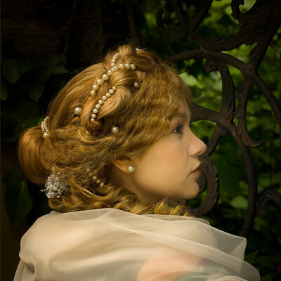 "Transport yourself to the Romantic Era with Lisa V., elegantly adorned in a chignon hairstyle and period attire. 💖 Photographer, makeup artist, and hairstylist: Anett Alexandra Bulano. #RomanticEra #VictorianFashion" "Portrait of Lisa V. dressed in a romantic style with a chignon and a pearled central plait. Styled and photographed by Anett Alexandra Bulano.